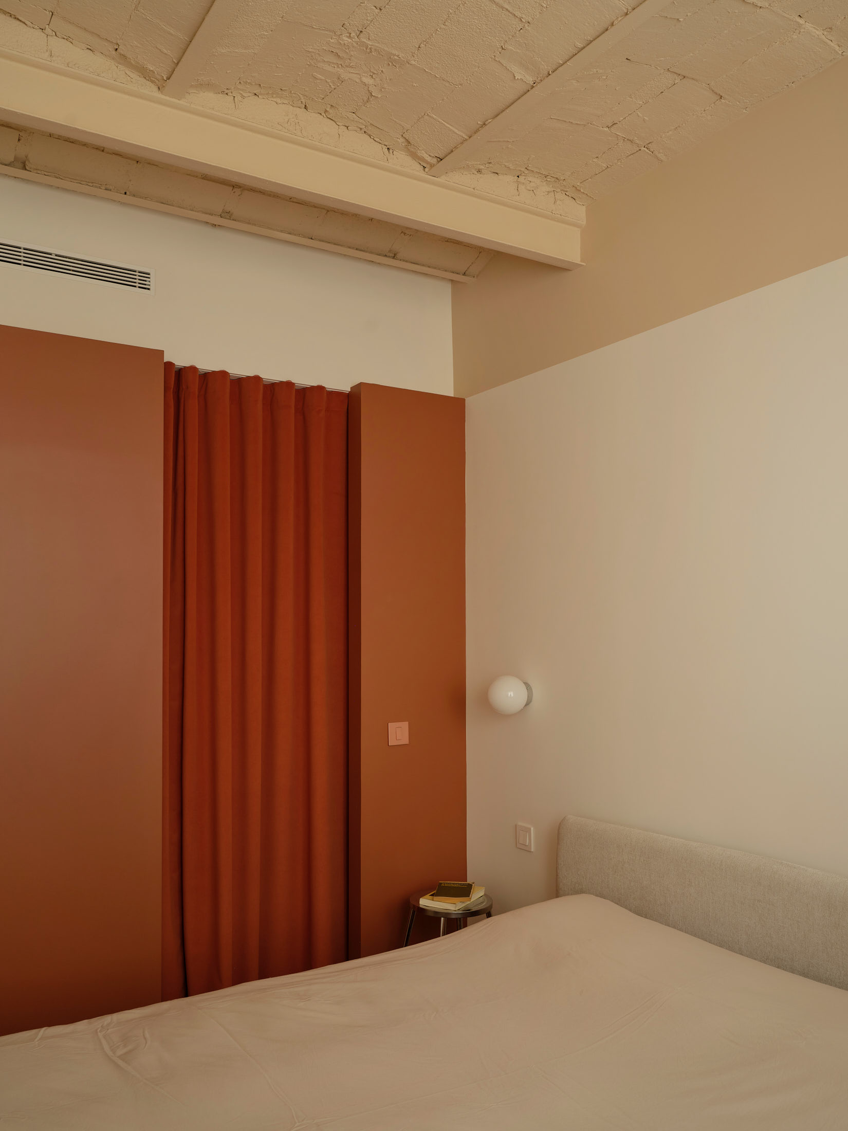 Viladomat Apartment in Barcelona by Colombo Architecture - bedroom with clay red curtain and bedside table